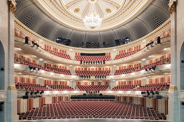 Prunkvoller Zuschauerraum der Staatsoper Unter den Linden mit roten Sitzen, Logenrängen und zentralem Kronleuchter.