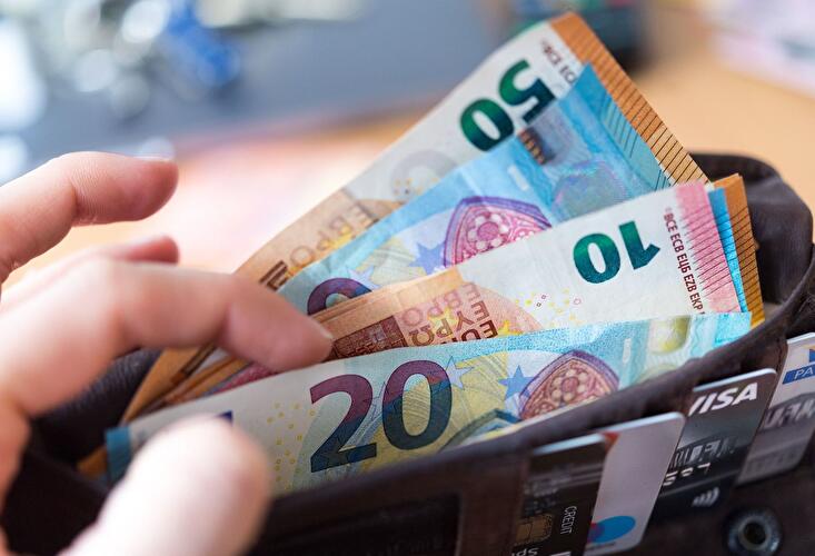 Eine Frau hält eine Geldbörse mit Banknoten in der Hand