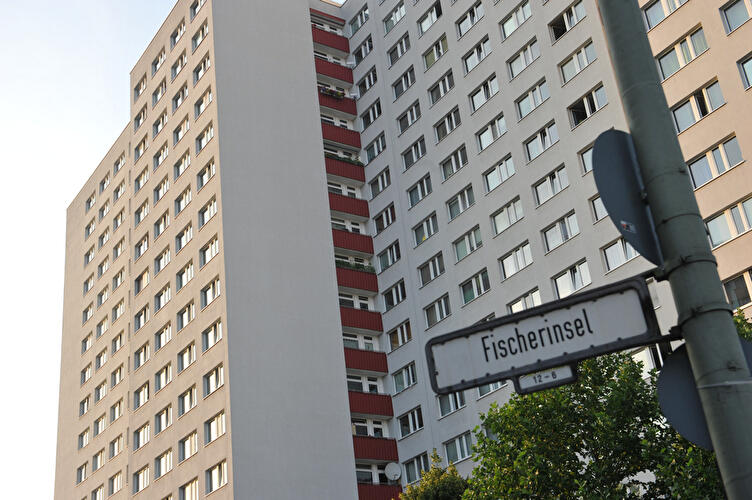 Hochhäuser der Fischerinsel in Berlin mit markanten roten Balkonen; im Vordergrund ein Straßenschild mit der Aufschrift „Fischerinsel“.