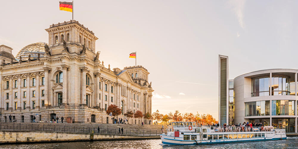 Ausflugsdampfer fährt auf der Spree im Herbst am Reichstagsgebäude vorbei.