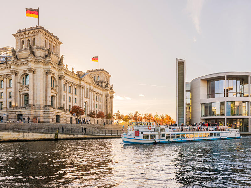 Ausflugsdampfer fährt auf der Spree im Herbst am Reichstagsgebäude vorbei.