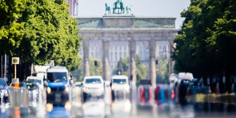 Autos fahren hinter dem Brandenburger Tor über die Straße