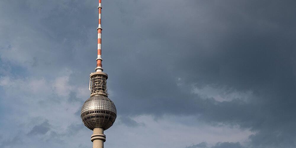 Berliner Fernsehturm vor dunklen Gewitterwolken am Himmel.