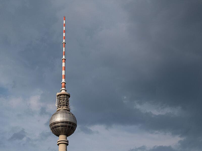 Berliner Fernsehturm vor dunklen Gewitterwolken am Himmel.