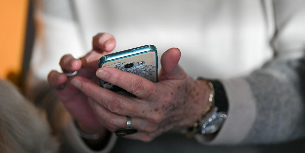 Person bedient ein Smartphone mit beiden Händen.