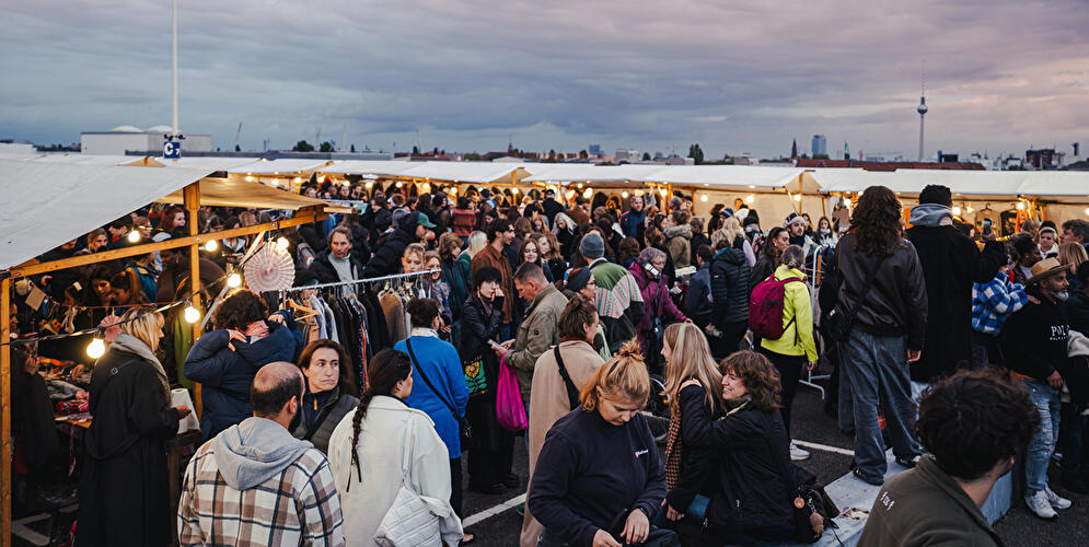 Viele Menschen gehen in den Abendstunden durch die Reihen der Flohmarktstände. 