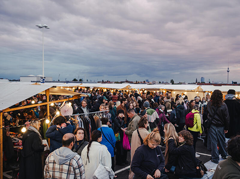 Viele Menschen gehen in den Abendstunden durch die Reihen der Flohmarktstände. 