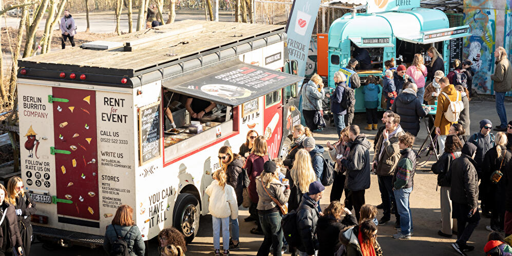 Street-Food-Besucherinnen und -Besucher stehen vor Foodtrucks.