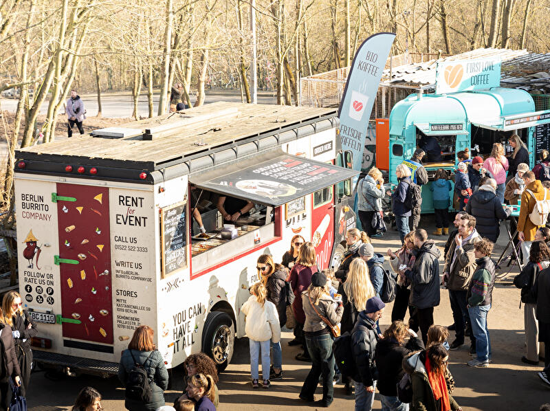 Street-Food-Besucherinnen und -Besucher stehen vor Foodtrucks.