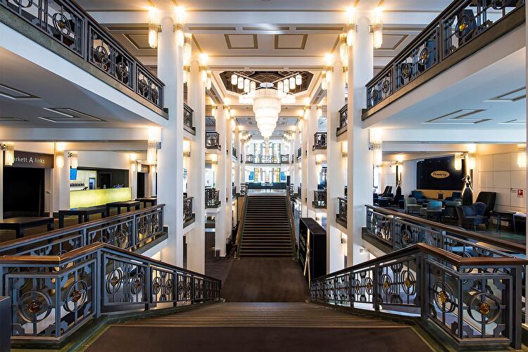 Foyer im Friedrichstadt-Palast Berlin mit Freitreppe, Säulen, Galerien und großen Kronleuchtern im Art-déco-Stil.