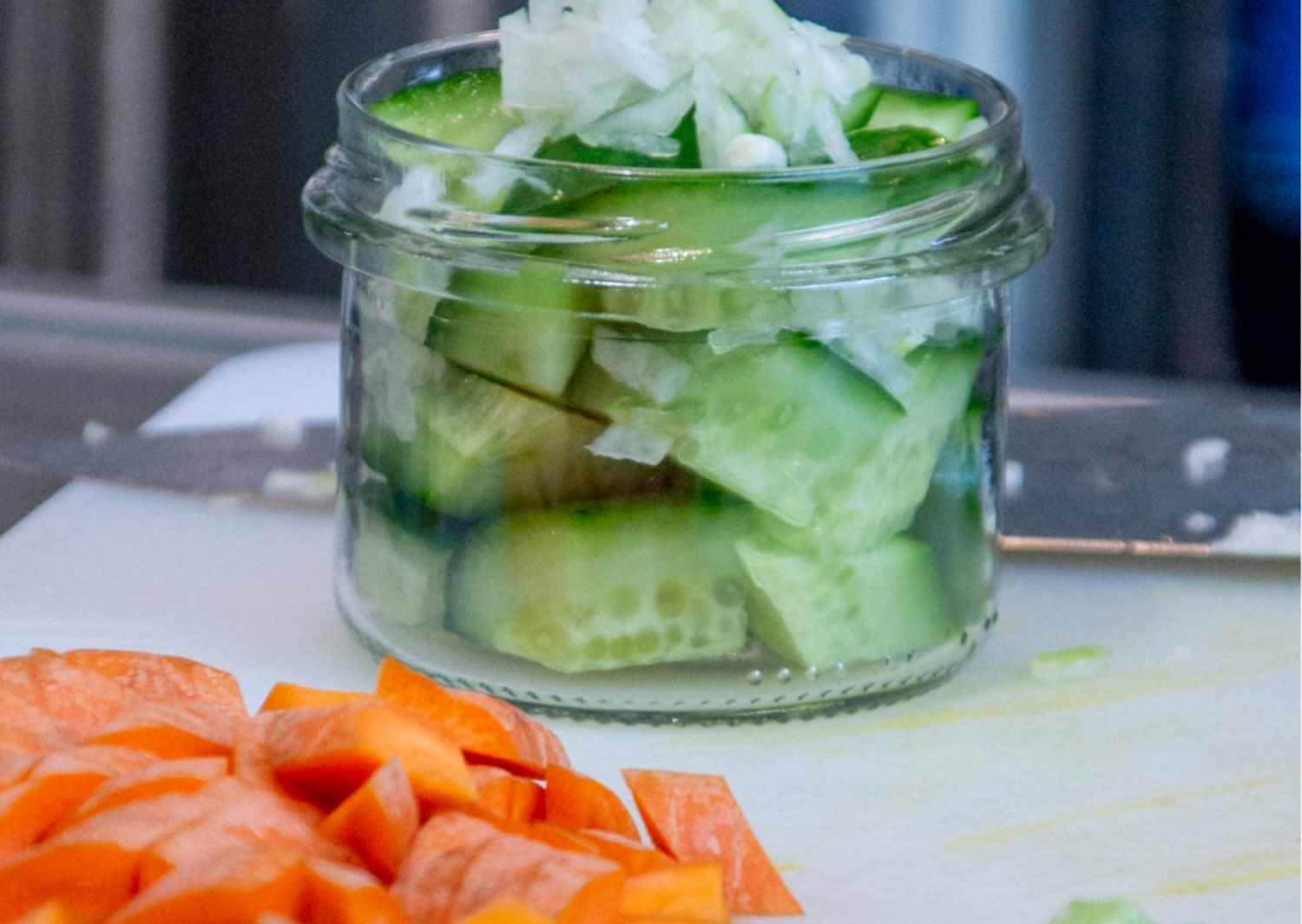 geschnittene grüne Gurken in einem Glas davor geschnittene Mohrrüben