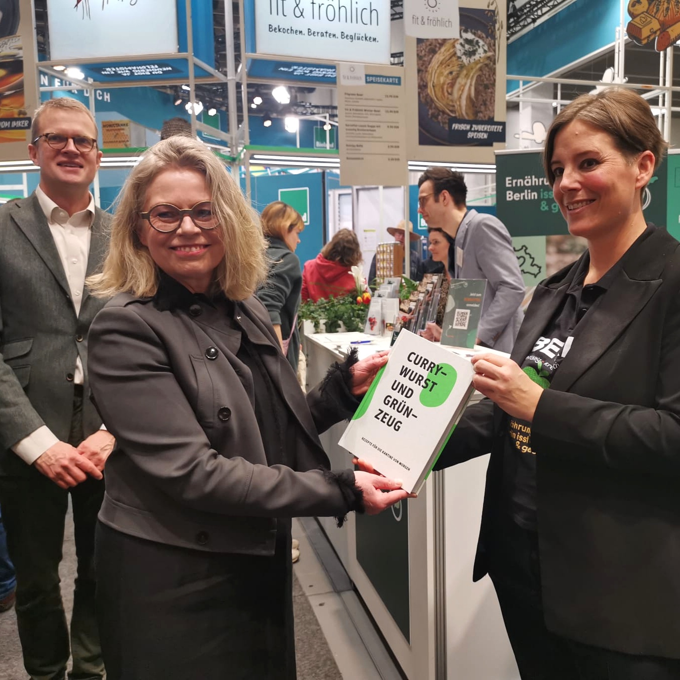 Senatorin Bonde bekommt das Kochbuch der Kantine Zukunft von einer Mitarbeiterin der Berliner Ernährungsstrategie überreicht