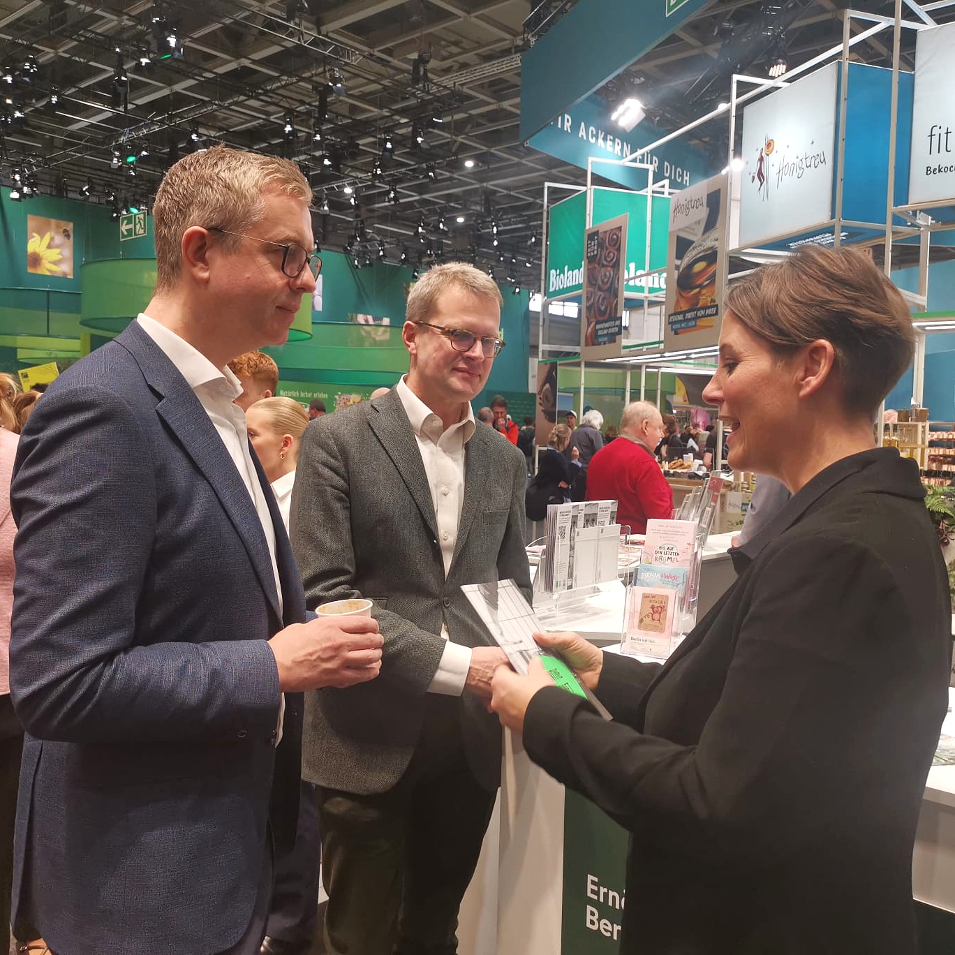 Finanzsenator Evers zu Gast in der Berlin-Halle am Stand der Berliner Ernährungsstrategie, ihm wird das Kochbuch der Kantine Zukunft überreicht