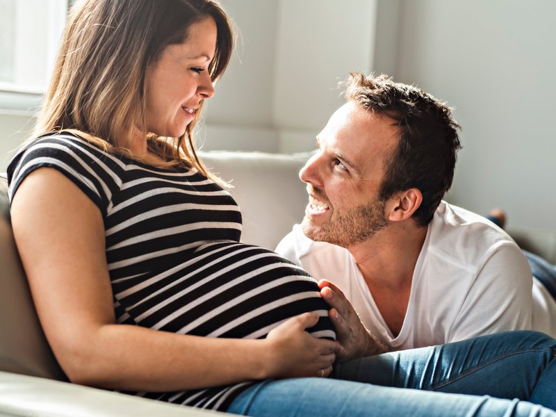 Werdender Vater lächelt seine schwangere Frau an