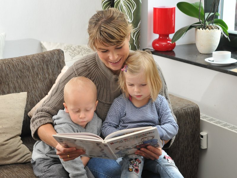 Frau liest zwei kleinen Kindern etwas vor