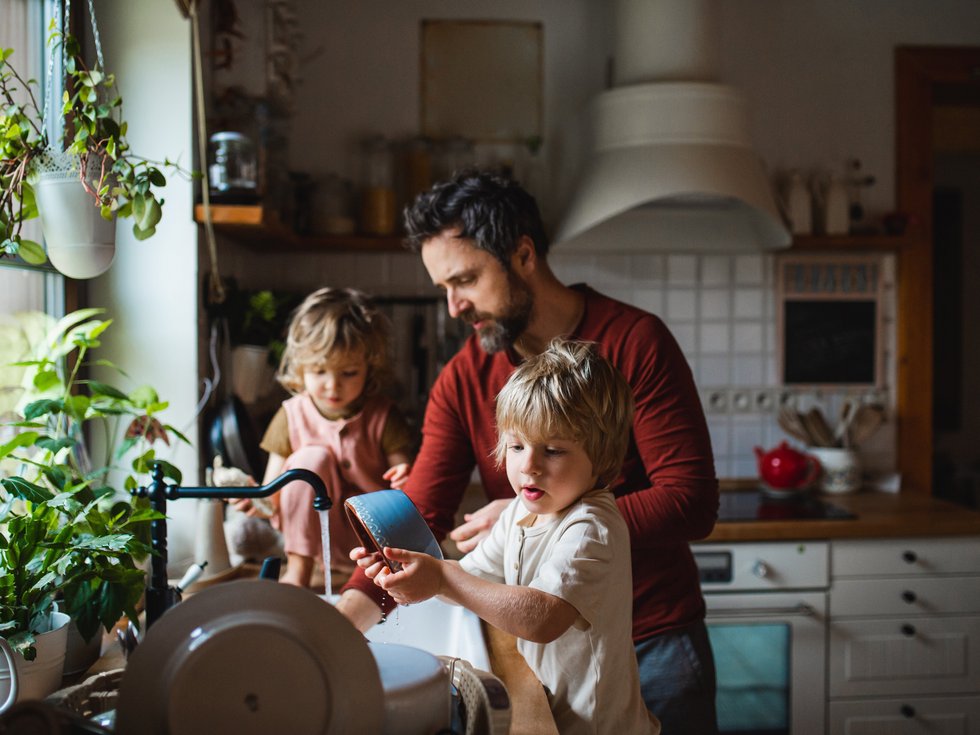 Vater mit zwei kleinen Kindern zu Hause in der Küche beschäftigt