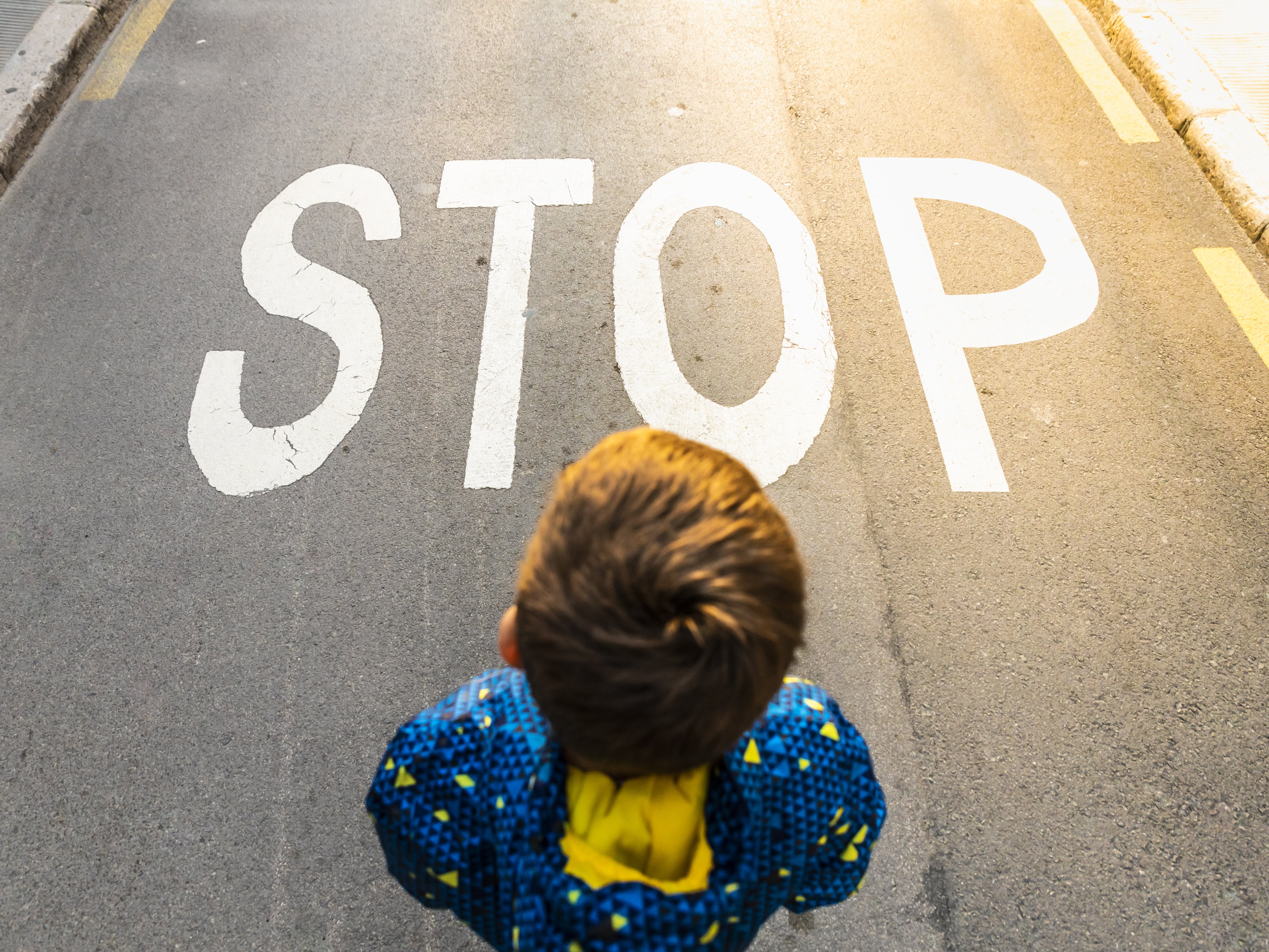 Kind steht vor einem Stop auf der Straße
