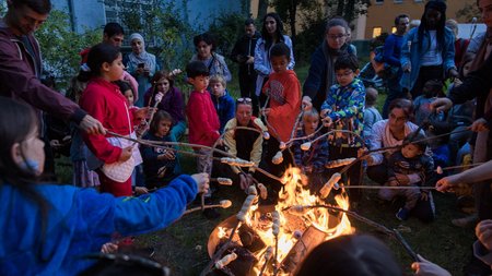 Kinder sitzen bei der Familiennacht mit Stockbrot um ein Lagerfeuer