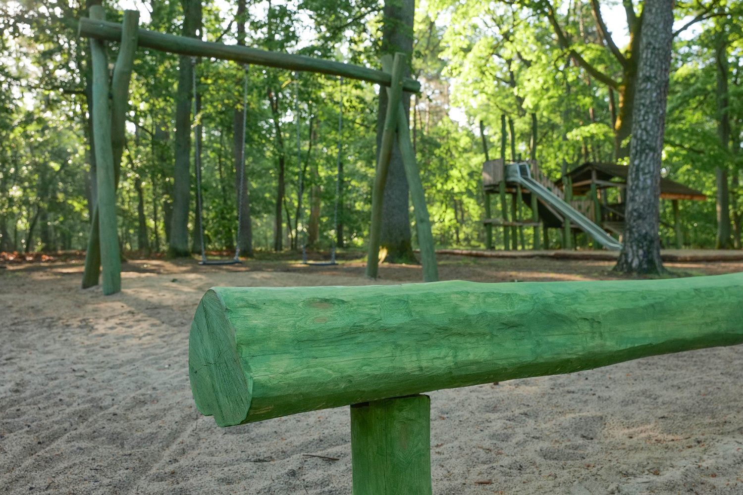 Waldspielplatz Promenade Teufelssee; Balancierbalken, im Hintergrund Schaukel und Rutsche