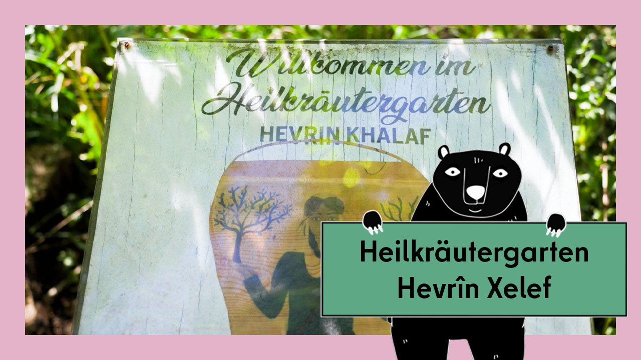 Vorschaubild für das Video Interkultureller Gemeinschaftsgärten: der Heilkräutergarten „Hevrîn Xelef” in Neukölln. Abgebildet ist ein Willkommensschild im Garten.