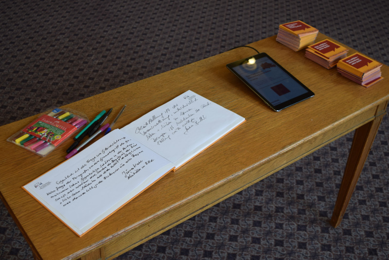 Auf dem Tisch das Gästebuch, Tablet mit der Umfrage und Minibooklets