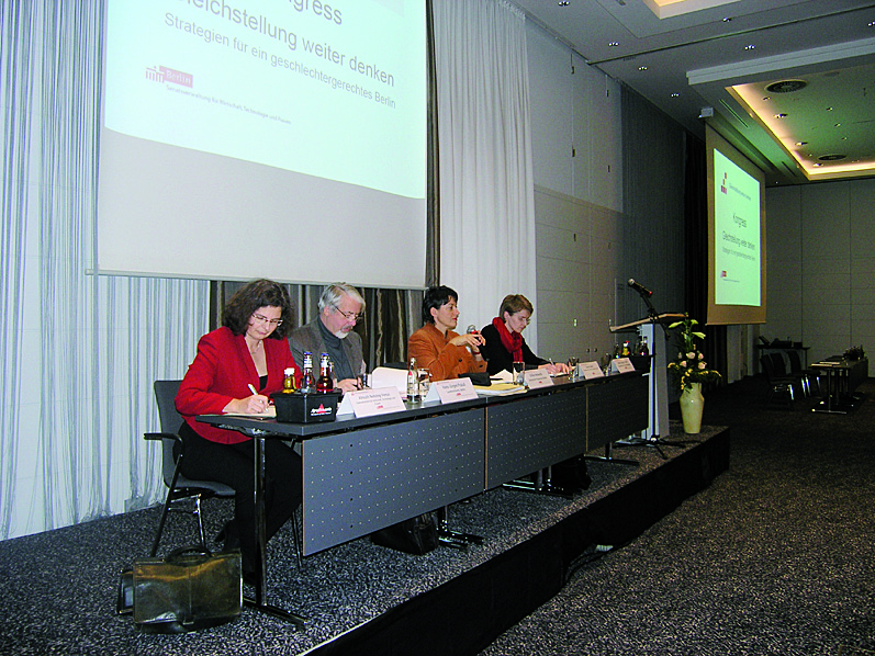 Podium mit vier Teilnehmerinnen während eines Vortrags