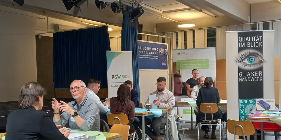 Teilnehmende im Gespräch an Tischen sitzend