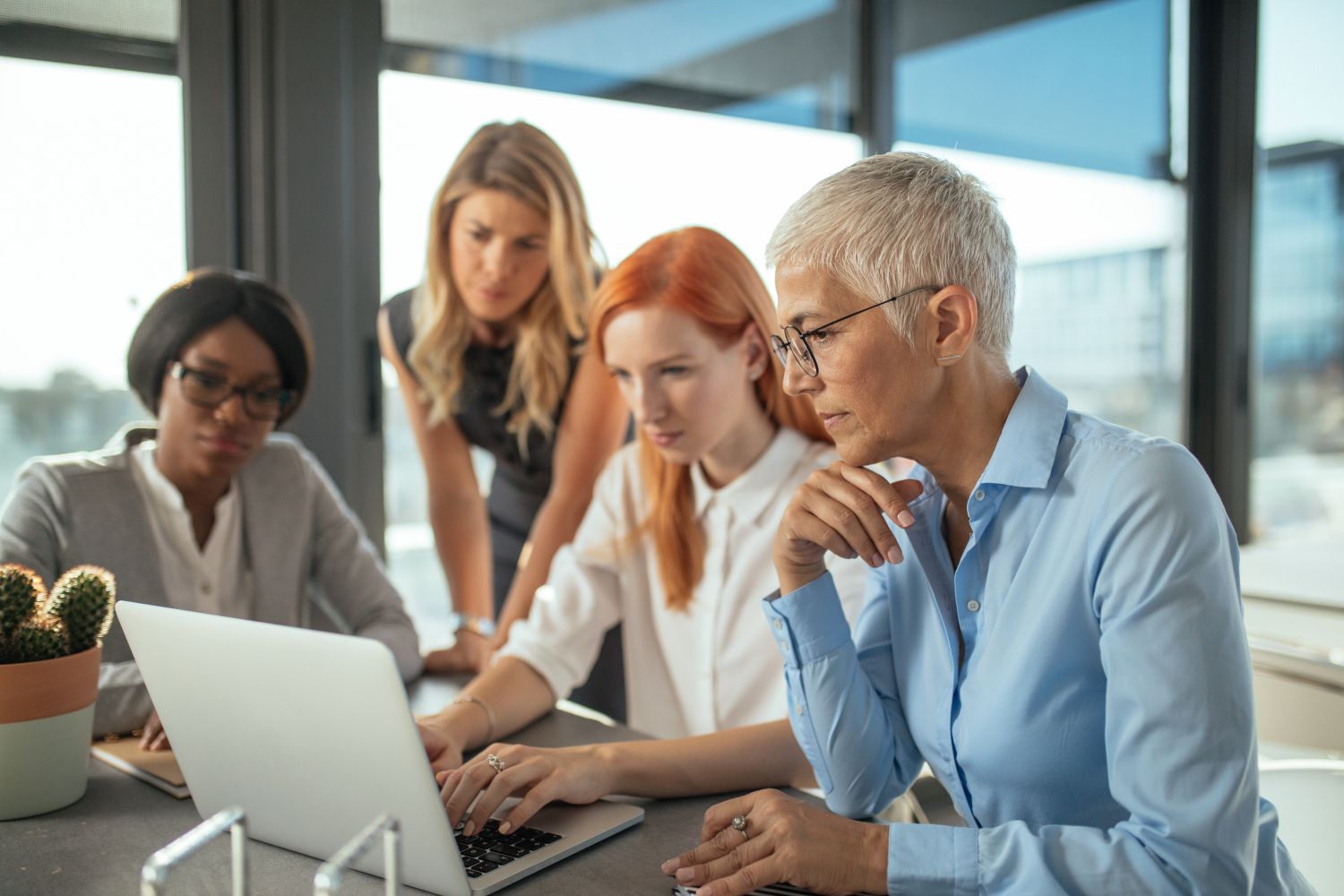 Gruppe von Unternehmerinnen arbeiten gemeinsam an einem Laptop