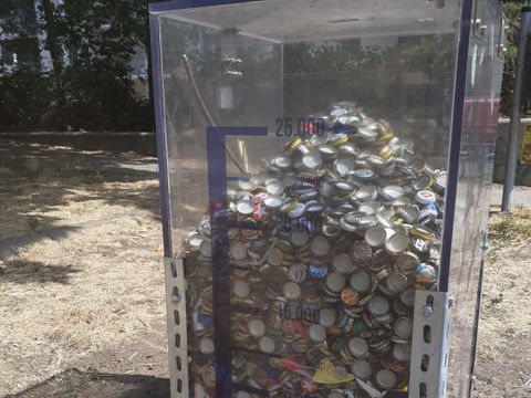 Ein durchsichtiger behälter in dem Kronkorken gesammelt werden können. Der behälter ist zu drei Vierteln gefüllt mit Kronkorken. Ein aufgedruckter Füllstandanzeiger zeigt, dass ca. 25.000 Kronkorken gesammelt wurden.