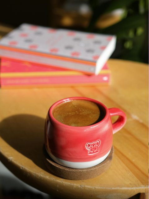 Fotografie einer Kaffeetasse auf einem Tisch mit Büchern im Hintergrund
