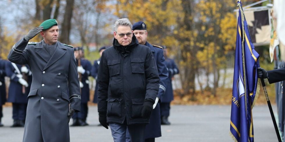 Zwei Männer laufen an einer Kompanie vorbei.