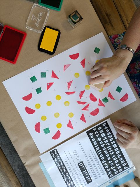 Person stempelt geometrische Formen in unterschiedlichen Farben