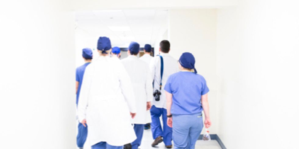 Ärzte und Pflegerinnen laufen einen Gang entlang