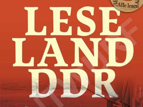 Bild des Ausstellungsplakates, das auf ochsenblutrotem Hintergrund den beigen Schriftzug "Leseland DER" zeigt, während im Hintergrund zwei Personen lesend am Strand auf dem Rücken liegen.
