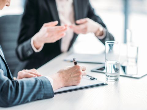 Zwei Frauen in Businesskleidung sitzen am Tisch und diskutieren