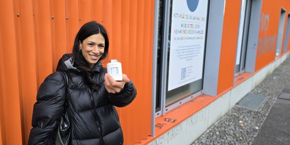 Zoe Naomi Hoffmann, Klimaschutzmanagerin in der OE Klima und Internationales, zeigt ein smartes Themostat vor dem Gebäude in der Ohlauer Straße