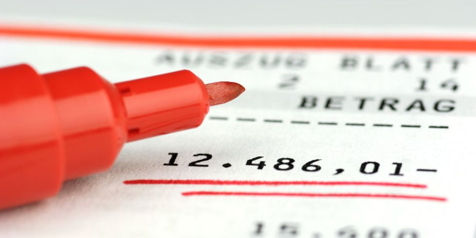 Kontoauszug zeigt einen unterstrichenen Minusbetrag von 12486,01 Euro an, daneben liegt ein Filzstift