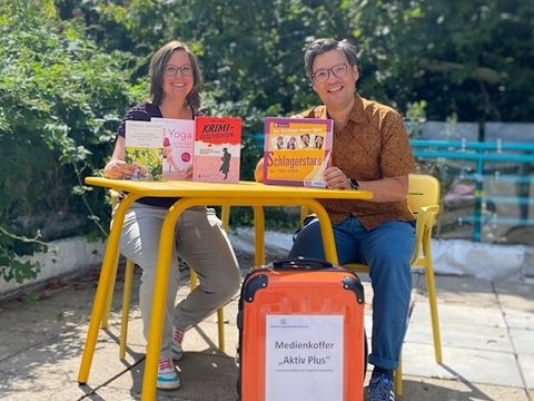 Miriam Sammet, Leitung der Zentralen Einarbeitung, und Dr. Boryano Rickum, Leitung der Stadtbibliothek Tempelhof-Schöneberg, mit dem Medienkoffer „Aktiv Plus“ (Bild: Stadtbibliothek Tempelhof-Schöneberg)