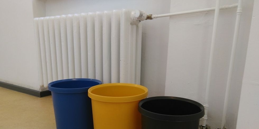 Leere Mülltonnen und Heizung unter einem Fenster