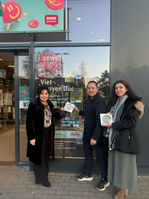 Bezirksbürgermeisterin Emine Demirbüken-Wegner, Herr Duc Viet Nguyen und Einsamkeitsbeauftragte Katharina Schulz beim Anbringen des Stickers gegen Einsamkeit