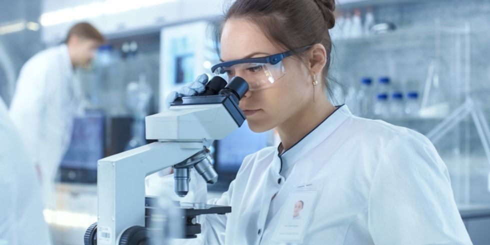Wissenschaftlerin schaut durch ein Mikroskop