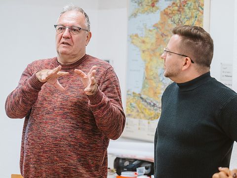 Teilnehmende diskutieren und gestikulieren stehend im Raum