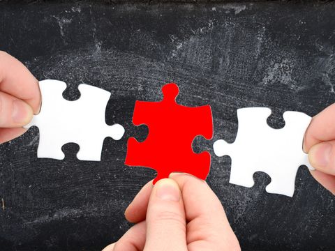 Drei Puzzleteile und Tafel mit Finger