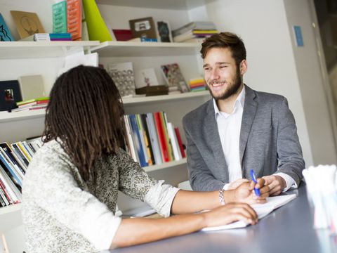 Zwei Personen sprechen miteinander. Sie sitzen in einem Büro.