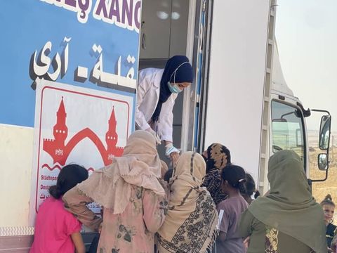 Eine Gruppe Menschen wird an einer mobilen Klinik in der Parnerstadt Dêrik versorgt