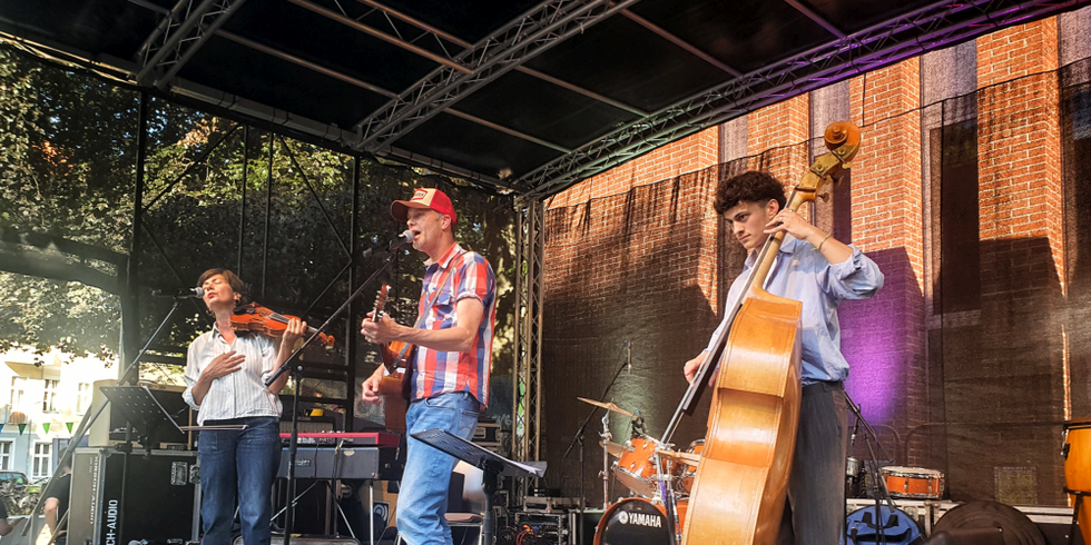 Eine drei köpfige Band spielt auf einer Bühne Musik
