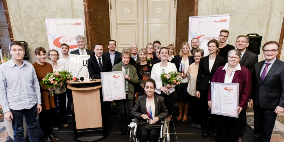 Die Preisträger des Berliner Inklusionspreises stehen gemeinsam auf der Bühne und schauen in die Kamera