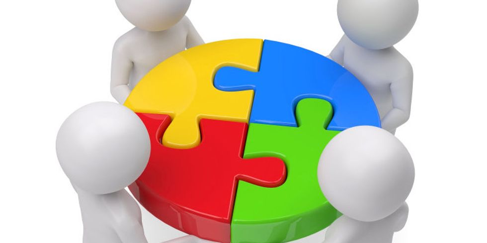 Vier Personen setzen einen Puzzlekreis zusammen 