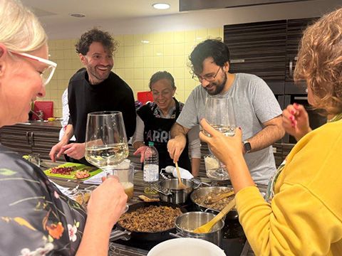 Teilnehmer und Kursleiterin umringen den Herd und lachen sich zu