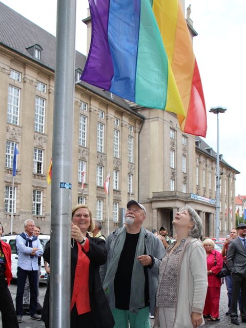 Bezirksbürgermeisterin Angelika Schöttler (l.) hisst die Regenbogenfahne unter den prüfenden Blicken von Dr. Elisabeth Ziemer (r.) und Gerhard Hoffmann (m.) (Bild: Pressestelle Tempelhof-Schöneberg)